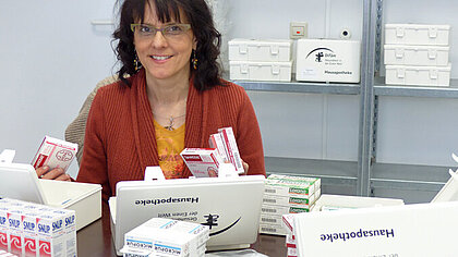 Haus- und Reiseapotheken Eine Frau sortiert Haus- und Reiseapotheken
