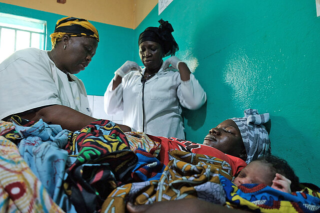 Versorgung von Mutter und Baby Hebamme und Krankenschwester betreuen eine junge Mutter und ihr Neugeborenes in Guinea