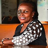 Vicky Abenakyo Porträtbild von Vicky Abenakyo (sitzend an einem Tisch)
