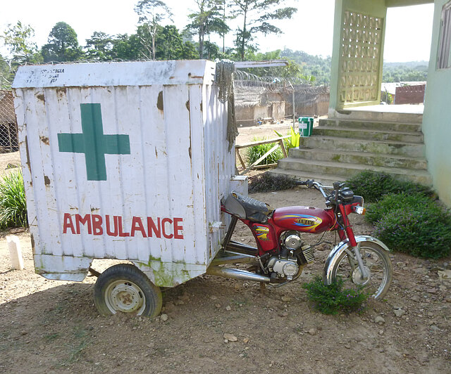 Ambulanz in Afrika Afrikanischer Krankentransport in Form eines Motorrads mit Anhänger mit einem platten Reifen